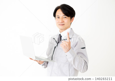 一位身穿灰色工作服的中年商人手持筆記型電腦,在白色背景下舉起食指。 一位身穿灰色工作服的中年商人手持筆記型電腦,在白色背景下舉起食指。 140283211
