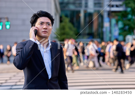 一名男性上班族在尖峰時段於商業區的十字路口收到智慧型手機上的緊急簡訊後，感到震驚和沮喪。 140283450