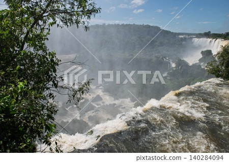 Majestic iguazu falls pouring water over cliff creating mist in breathtaking wild nature Majestic iguazu falls pouring water over cliff creating mist in breathtaking wild nature 140284094