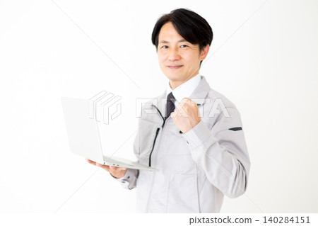 一位身穿灰色工作服的中年商務人士在白色背景前,手持筆記型電腦,做出勝利的手勢。 一位身穿灰色工作服的中年商務人士在白色背景前,手持筆記型電腦,做出勝利的手勢。 140284151