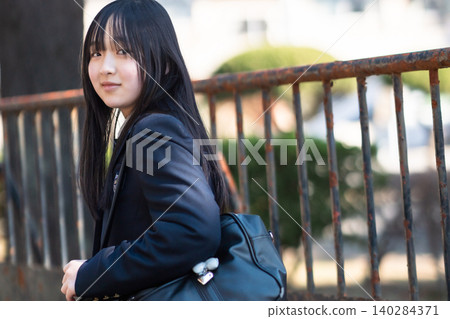 A high school girl in a blazer uniform smiles as she looks back on her way to school. A high school girl in a blazer uniform smiles as she looks back on her way to school. 140284371