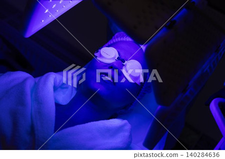 Woman undergoing blue light therapy treatment in a wellness center Woman undergoing blue light therapy treatment in a wellness center 140284636