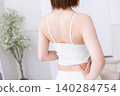 The back view of a woman wearing a white tank top. 140284754
