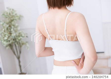 The back view of a woman wearing a white tank top. The back view of a woman wearing a white tank top. 140284754