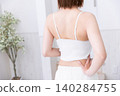 The back view of a woman wearing a white tank top. 140284755