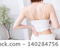 The back view of a woman wearing a white tank top. 140284756