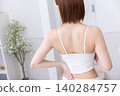 The back view of a woman wearing a white tank top. 140284757