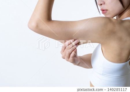 A fit, stylish woman who works out; a Japanese woman pinching her upper arm to check for sagging; dieting. 140285117