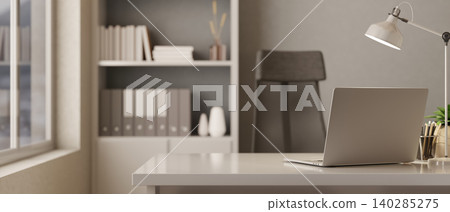 Laptop with lamp and pencils on white table and black net chair beside bookshelf in grey wall office Laptop with lamp and pencils on white table and black net chair beside bookshelf in grey wall office 140285275