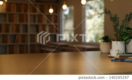 Wooden table with coffee cup and book beside potted plant across bookshelf and window in dim library Wooden table with coffee cup and book beside potted plant across bookshelf and window in dim library 140285297