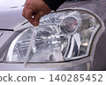 Removing masking tape after headlight cleaning. 140285452