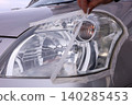 Removing masking tape after headlight cleaning. 140285453