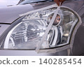 Removing masking tape after headlight cleaning. 140285454