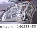 Removing masking tape after headlight cleaning. 140285455