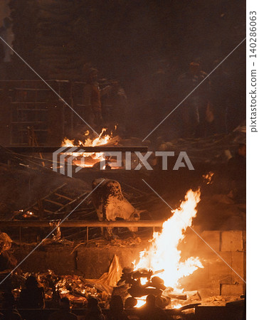 Varanasi, Uttar Pradesh, India. Cremation in process on Manikarnika Ghat. Cow Near Burning Pyre in Varanasi Varanasi, Uttar Pradesh, India. Cremation in process on Manikarnika Ghat. Cow Near Burning Pyre in Varanasi 140286063