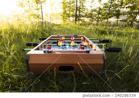 Foosball table in tall grass in a garden, reflecting everyday recreation as a prelude to the upcoming global soccer championship Foosball table in tall grass in a garden, reflecting everyday recreation as a prelude to the upcoming global soccer championship 140286339