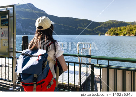 Woman standing on a pier at Lake Wolfgangsee in the Austrian Alps, reflecting seasonal adventure and an active outdoor lifestyle Woman standing on a pier at Lake Wolfgangsee in the Austrian Alps, reflecting seasonal adventure and an active outdoor lifestyle 140286343