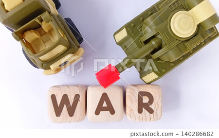 Top view of a military toy tank with wooden cubes labeled WAR. Illustration of war and conflict. Top view of a military toy tank with wooden cubes labeled WAR. Illustration of war and conflict. 140286682