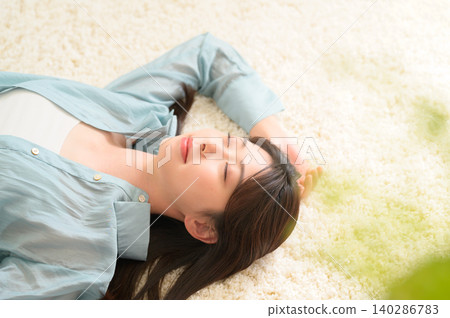 一位面帶微笑的日本女子躺在地板上。 一位面帶微笑的日本女子躺在地板上。 140286783