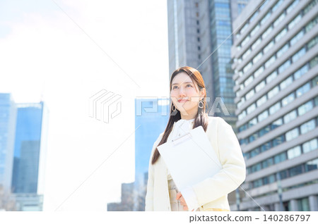一位日本女商人手持寫字板出現在辦公區。 一位日本女商人手持寫字板出現在辦公區。 140286797