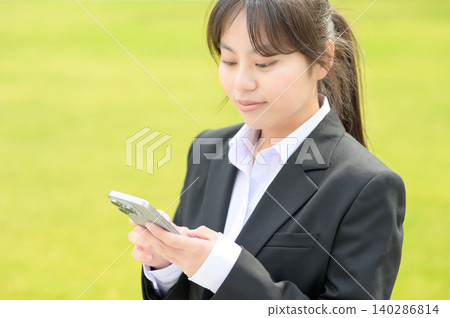 Japanese female office worker in her 20s using a smartphone Japanese female office worker in her 20s using a smartphone 140286814