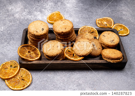 Homemade oatmeal cookies and dried orange slices on wooden tray Homemade oatmeal cookies and dried orange slices on wooden tray 140287823