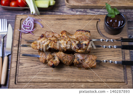 Traditional Russian shashlik on skewers with vegetables. Grilled pork meat (shish kebab). Close-up. 140287893