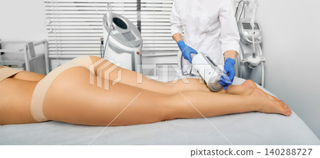 Woman while endospheres therapy and legs massage. Anti-cellulite massage at a beauty center Woman while endospheres therapy and legs massage. Anti-cellulite massage at a beauty center 140288727