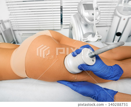 Ultrasound fat cavitation. Fat reduction treatment for woman's leg, and body contouring with cavitation machine Ultrasound fat cavitation. Fat reduction treatment for woman's leg, and body contouring with cavitation machine 140288731