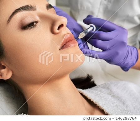 Lip augmentation procedure. Filler injection for beautiful woman lip augmentation with hyaluronic, side view Lip augmentation procedure. Filler injection for beautiful woman lip augmentation with hyaluronic, side view 140288764