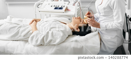 Facial microcurrent therapy. Microcurrent procedure for a female face at cosmetology salon Facial microcurrent therapy. Microcurrent procedure for a female face at cosmetology salon 140288774