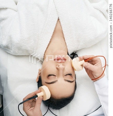 Beautiful woman receives microcurrent procedure for a facelift. Skin rejuvenation and face lift with microcurrent therapy Beautiful woman receives microcurrent procedure for a facelift. Skin rejuvenation and face lift with microcurrent therapy 140288776