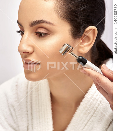 Facial roller massager. Woman getting procedure facial rejuvenation and lifting with face roller massager, high quality 140288780
