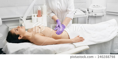 Doctor palpates a young woman's belly in a medical clinic. Physician doing a medical examination for female body for disease prevention Doctor palpates a young woman's belly in a medical clinic. Physician doing a medical examination for female body for disease prevention 140288798