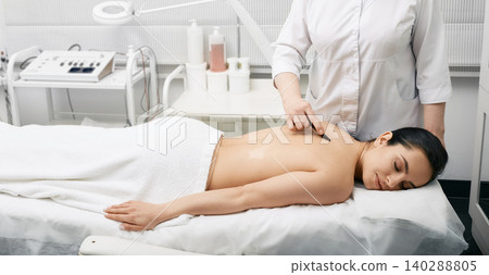 Chinese massage gouache. Woman while back gouache massage for body detoxify Chinese massage gouache. Woman while back gouache massage for body detoxify 140288805