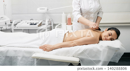 Gouache massage. Doctor doing a physical effect on woman's body using a gouache scraper for increased blood and lymph flow Gouache massage. Doctor doing a physical effect on woman's body using a gouache scraper for increased blood and lymph flow 140288806