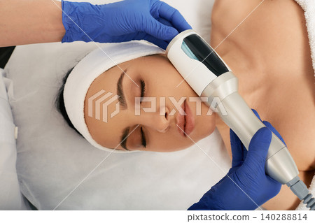 Cropped woman's face during facial endospheres therapy for correction oval face with a cosmetologist Cropped woman's face during facial endospheres therapy for correction oval face with a cosmetologist 140288814