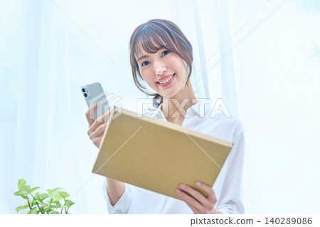 一位穿著白襯衫的女子,手裡拿著行李和智慧型手機,微笑著看著我。 一位穿著白襯衫的女子,手裡拿著行李和智慧型手機,微笑著看著我。 140289086