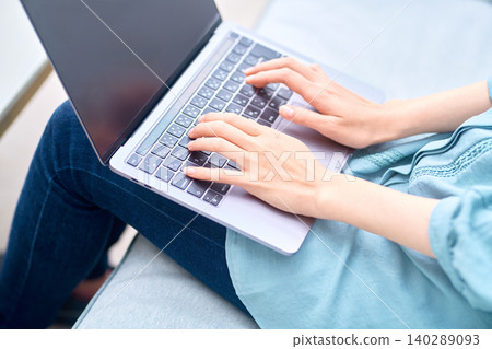A woman's hands typing on a laptop on her lap. A woman's hands typing on a laptop on her lap. 140289093