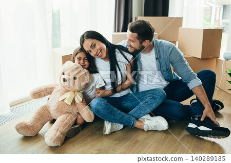 Happy couple with child while sitting at floor in new house Happy couple with child while sitting at floor in new house 140289185
