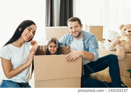 Happy couple unpacking boxes and having fun with daughter in living room at new home Happy couple unpacking boxes and having fun with daughter in living room at new home 140289197