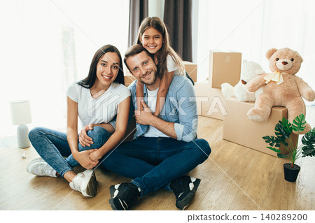 Happy family having fun while moving into new apartment. Mother, father and daughter together smiling, with Cardboard boxes on background Happy family having fun while moving into new apartment. Mother, father and daughter together smiling, with Cardboard boxes on background 140289200