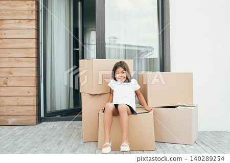 little girl playing with cardboard box at backyard. moving into new house little girl playing with cardboard box at backyard. moving into new house 140289254
