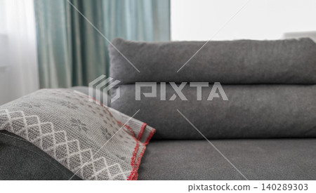 Dark grey modern sofa with a grey patterned throw blanket Dark grey modern sofa with a grey patterned throw blanket 140289303
