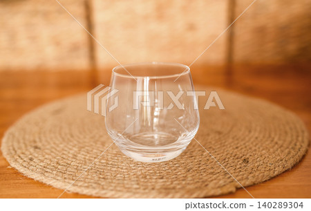 Empty clear water glass on a round coaster on a wooden table Empty clear water glass on a round coaster on a wooden table 140289304