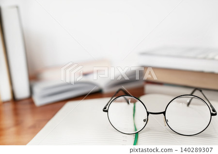 Close up of reading glasses on an open book with blurred background Close up of reading glasses on an open book with blurred background 140289307
