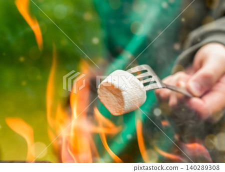 Close up of roasting marshmallow on a fork over outdoor fire pit 140289308