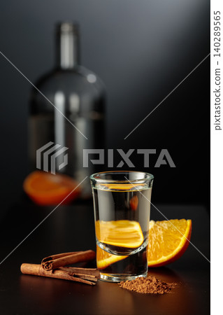 Mexican gold tequila with an orange slice and cinnamon on a black table. Mexican gold tequila with an orange slice and cinnamon on a black table. 140289565
