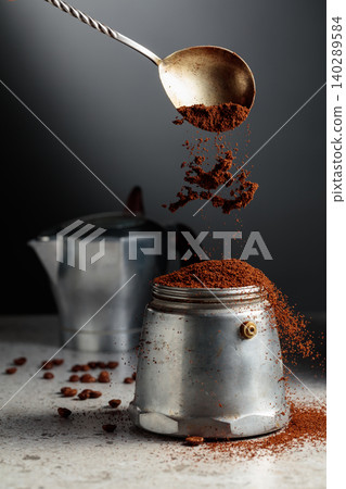Grounded coffee is poured into a classic Italian aluminium moka pot, models from the 1950s to the 1960s. Grounded coffee is poured into a classic Italian aluminium moka pot, models from the 1950s to the 1960s. 140289584
