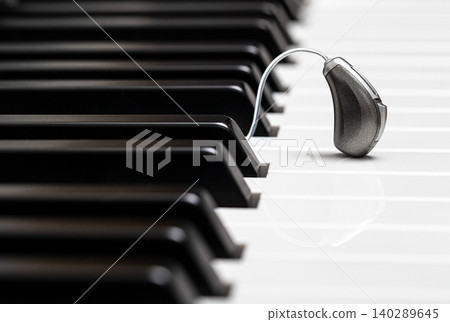 Close-up hearing aid on piano keys. Treatment of deafness. Hearing solution, hear all the variety of sounds in the world Close-up hearing aid on piano keys. Treatment of deafness. Hearing solution, hear all the variety of sounds in the world 140289645